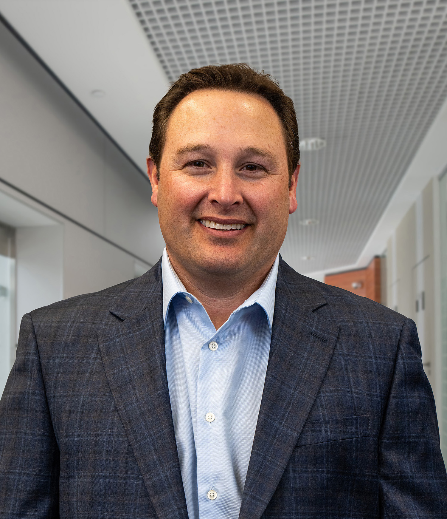Light skinned man named Mike with short brown hair wearing a light blue shirt and charcoal grey jacket.